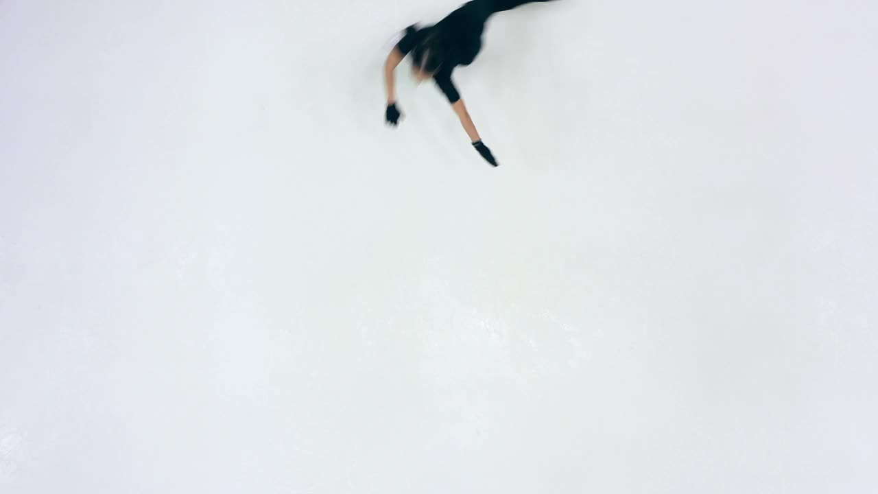 花样滑冰运动员一边滑冰一边在溜冰场上做各种旋转动作视频下载