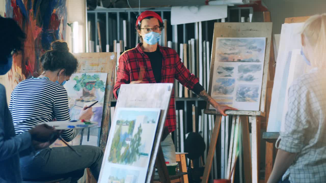 艺术教育理念。戴着口罩的男画家正在给女学生讲解绘画视频下载