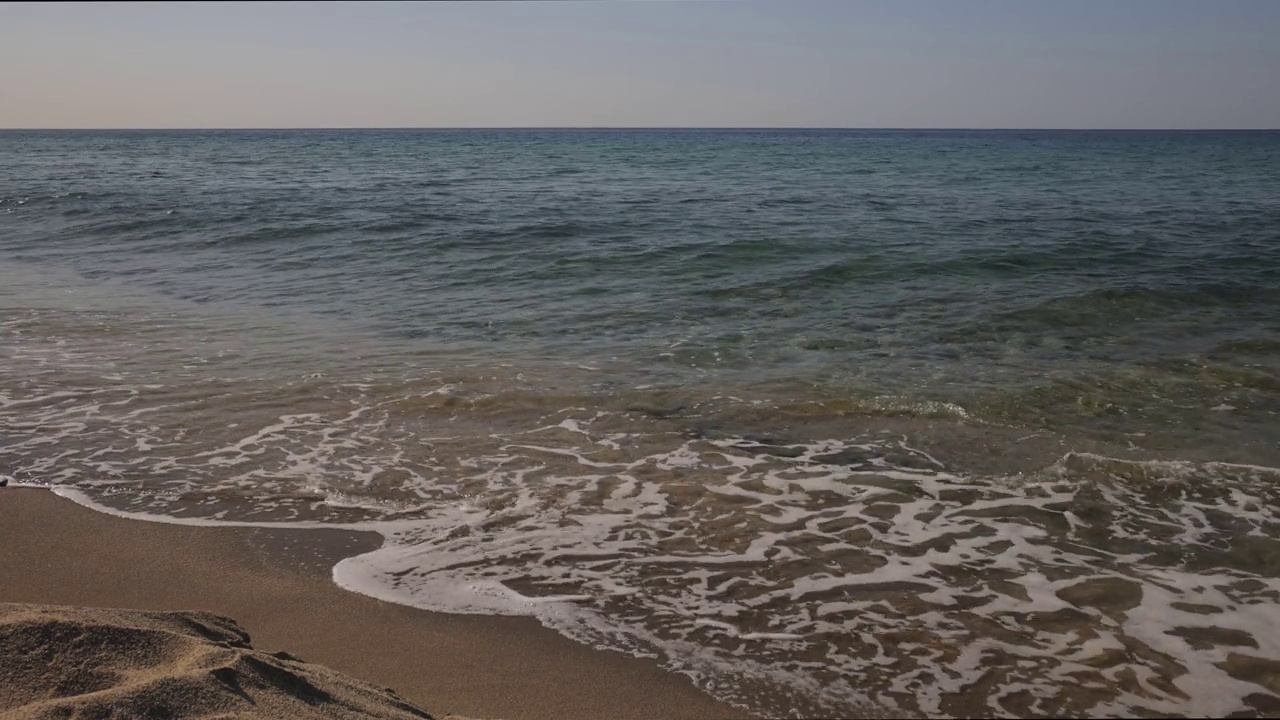 美丽的海浪轻轻地拍打着沙滩。视频下载
