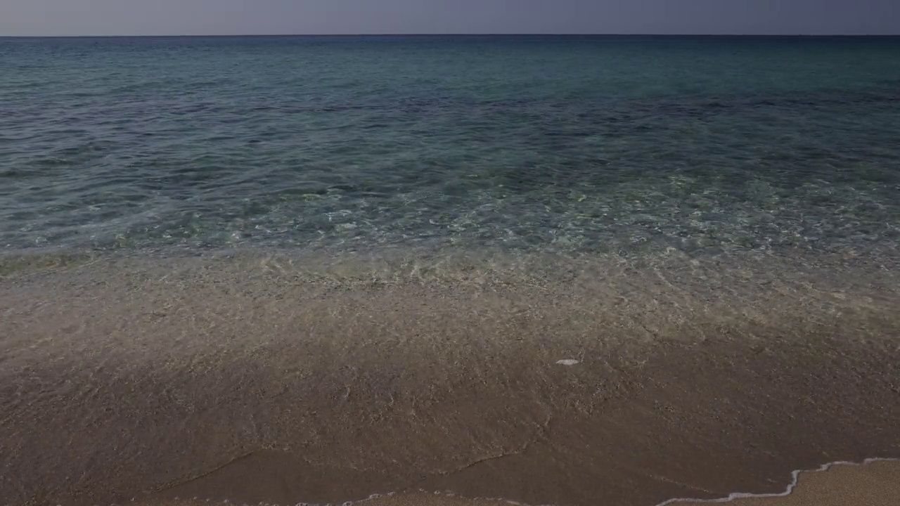 美丽的海浪轻轻地拍打着沙滩。视频下载