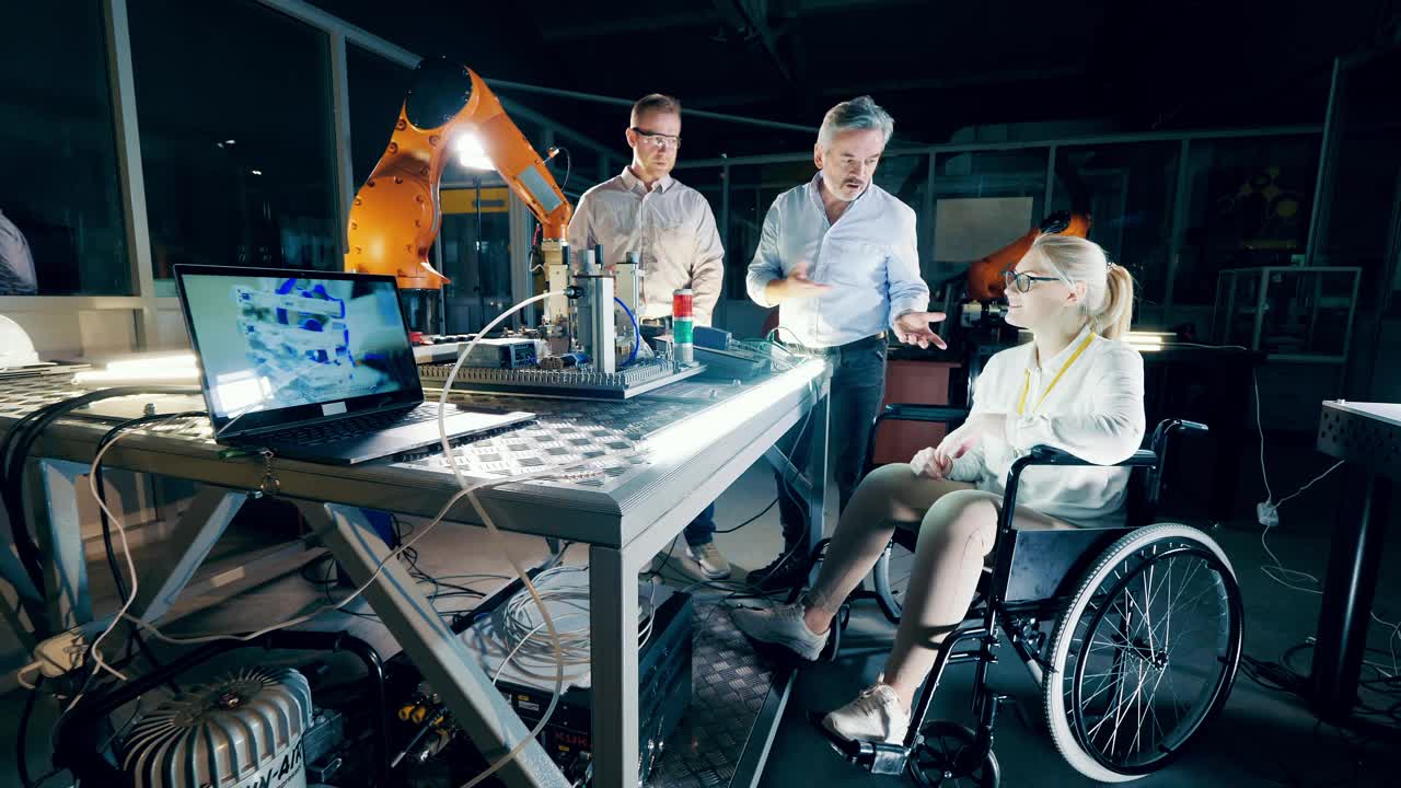 工厂的工程师们在现代化的设施里谈话，一个坐在轮椅上视频素材