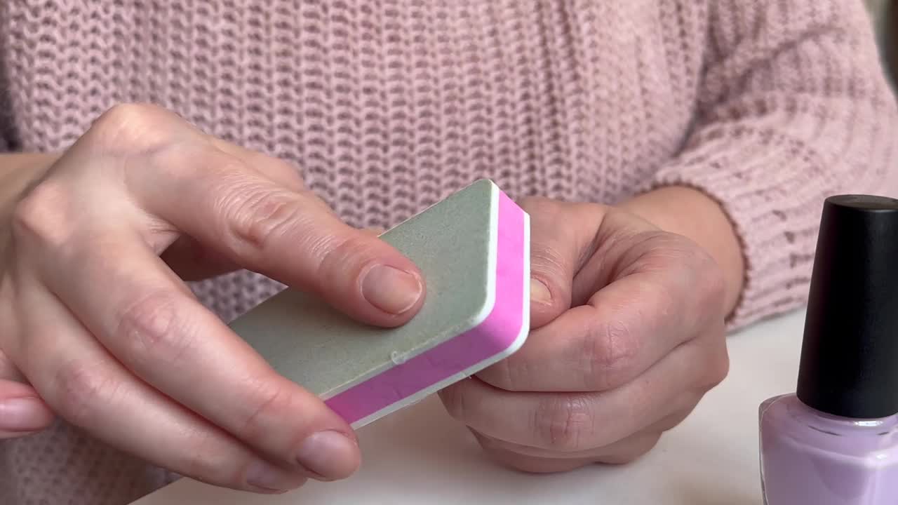 在家修指甲时，一个女人用手把指甲锉平视频下载