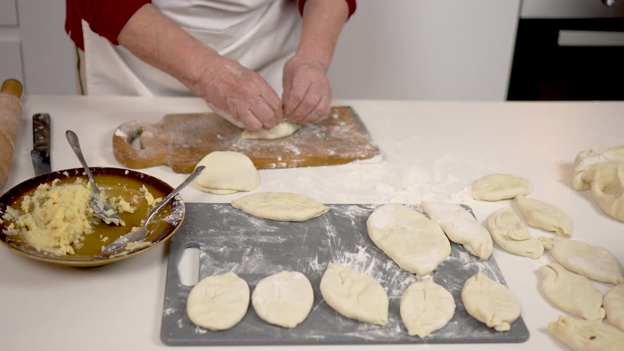 女厨师快速而熟练地用酵母面团包饺子在家烘烤。传统的美食视频下载