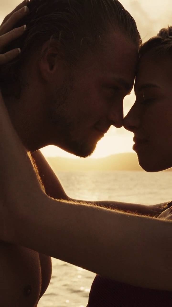 浪漫的夫妇在日落时在海边接吻的特写-垂直视频/詹姆斯比岛，多巴哥群岛，圣文森特和格林纳丁斯视频下载