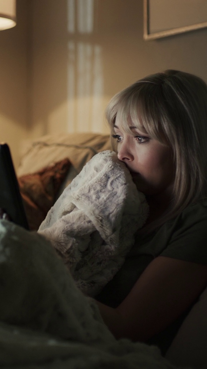 女人在沙发上播放恐怖电影的数字平板电脑-垂直视频/雪松山，犹他州，美国视频下载
