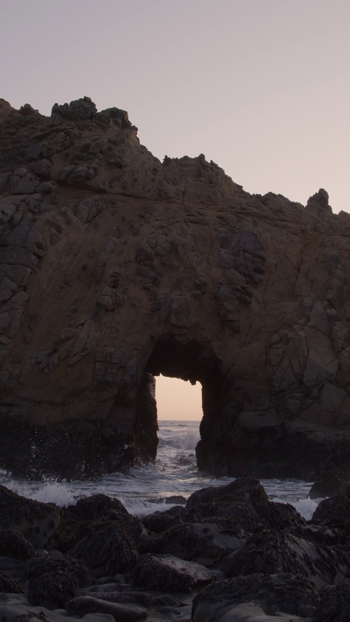 在日落时，海浪溅过钥匙孔拱门-垂直视频/大苏尔，加利福尼亚，美国视频下载