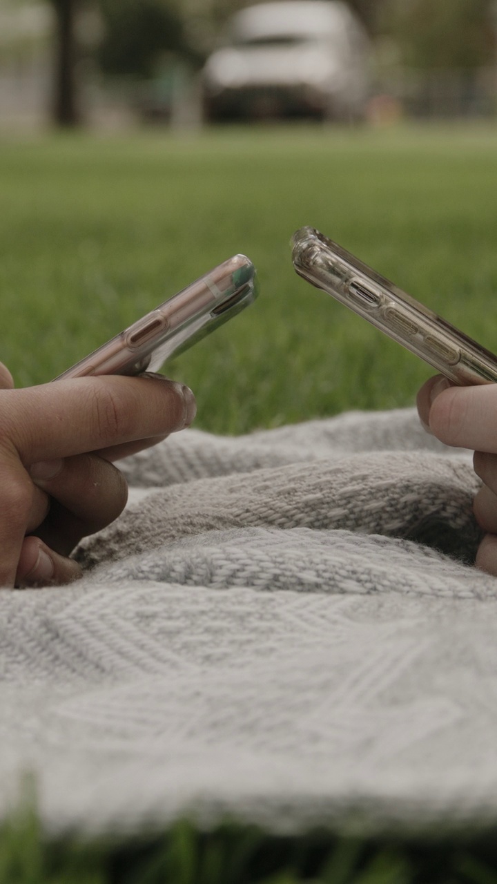 公园里躺在毯子上发短信的女孩的手特写——垂直视频/美国犹他州普罗沃视频下载