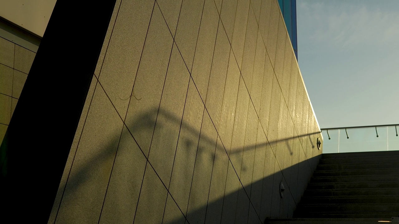 阴影和阳光投射在带有楼梯栏杆阴影的现代建筑米色墙上。视频素材