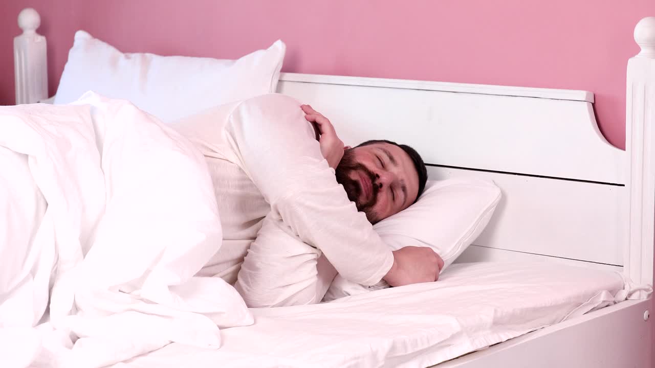 有胡子的帅哥在床上醒来。视频下载
