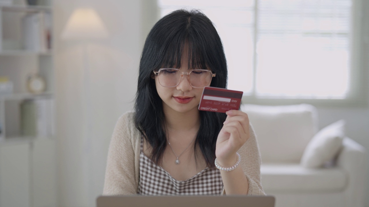 女子拿着信用卡在网上购物。在家工作的亚洲女性。网上购物，电子商务，网上银行，消费，在家工作的概念。视频下载