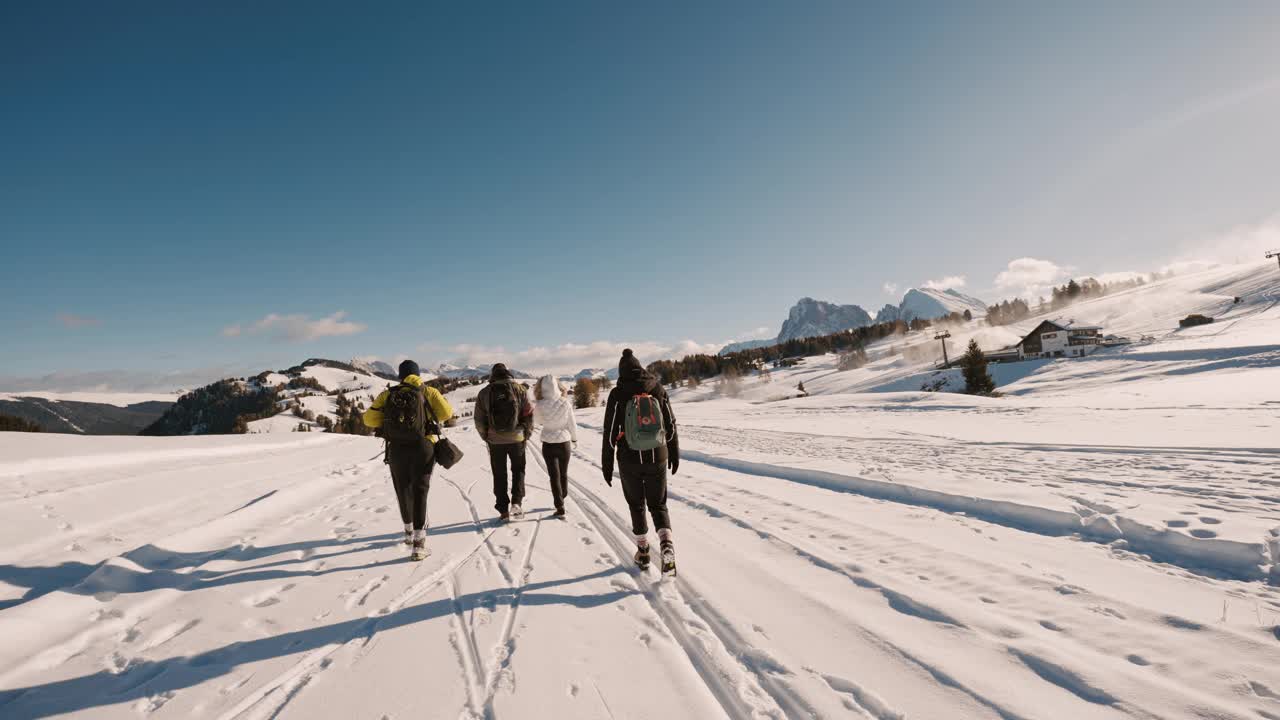 在白云石蓝天下的雪景中，穿着保暖衣服的未知徒步旅行者的后视图视频素材