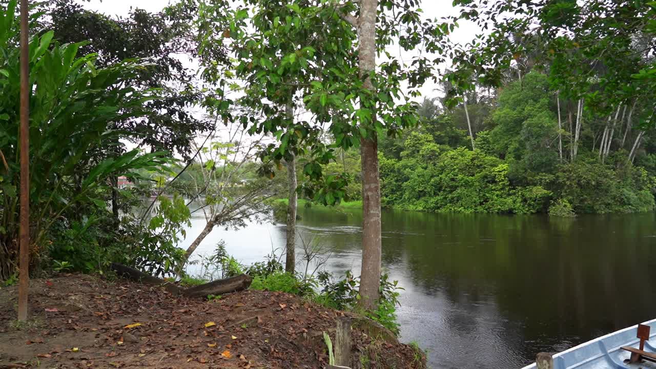 在热带亚马逊雨林地区的厄瓜多尔，沿着cuyabeno河的一个土著村庄，一艘小摩托艇躺在河岸上。视频下载