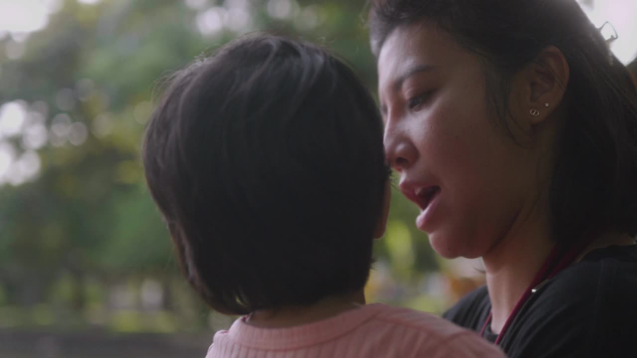 亚洲母亲在公园抱着儿子。放松与大自然的快乐时光。视频下载