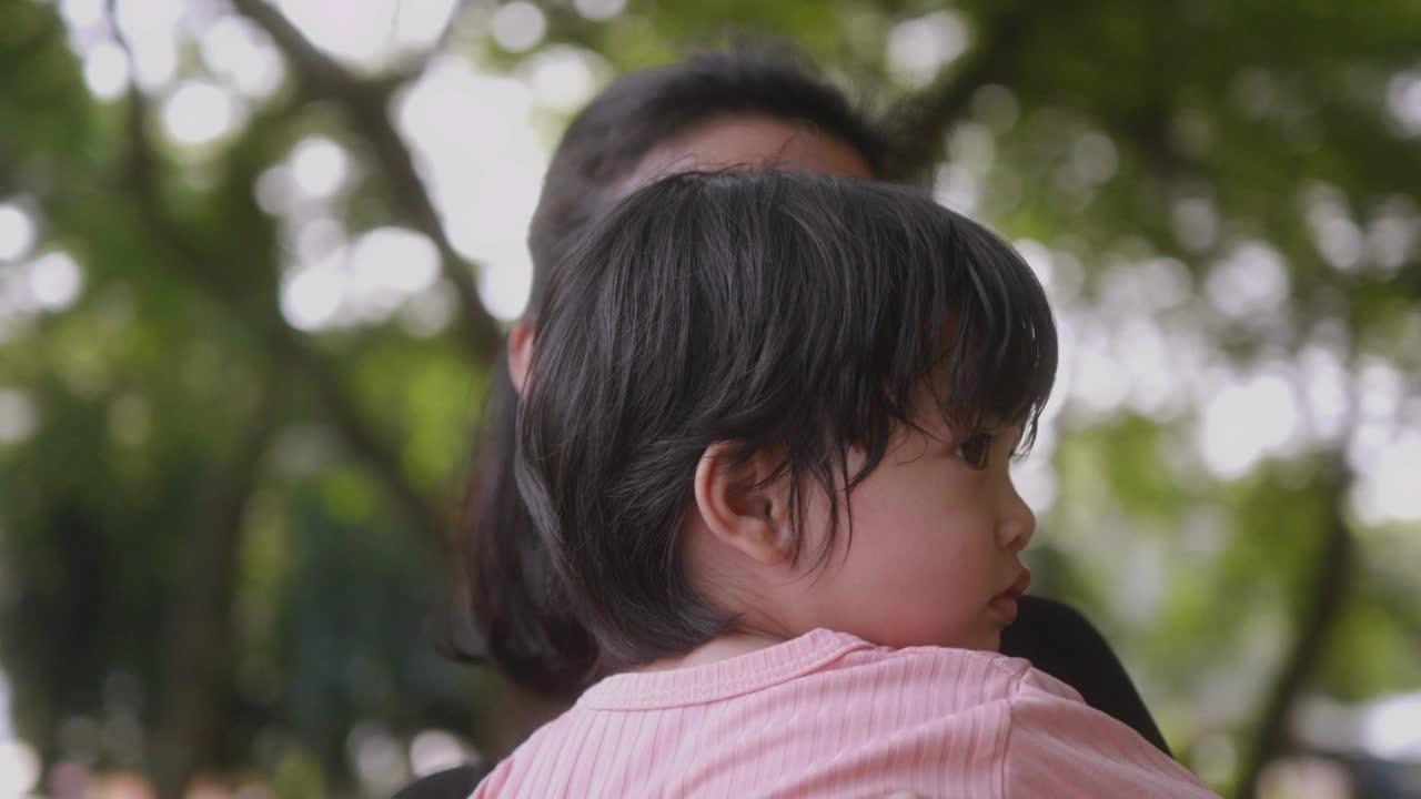 亚洲母亲在公园抱着儿子。放松与大自然的快乐时光。视频下载