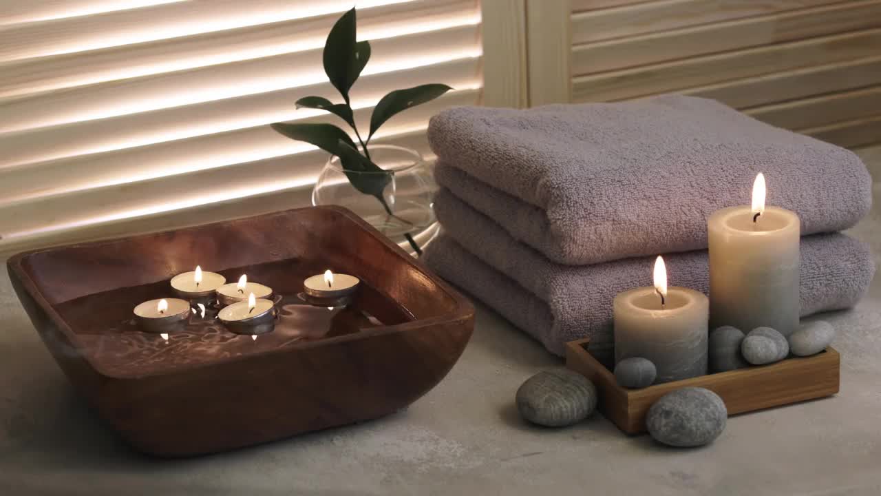 白色木桌上的美容水疗项目。蜡烛、石头、盛水的碗和毛巾。舒适的澡。视频下载