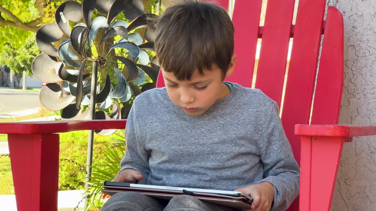 小男孩坐在自家前院玩平板电脑视频下载