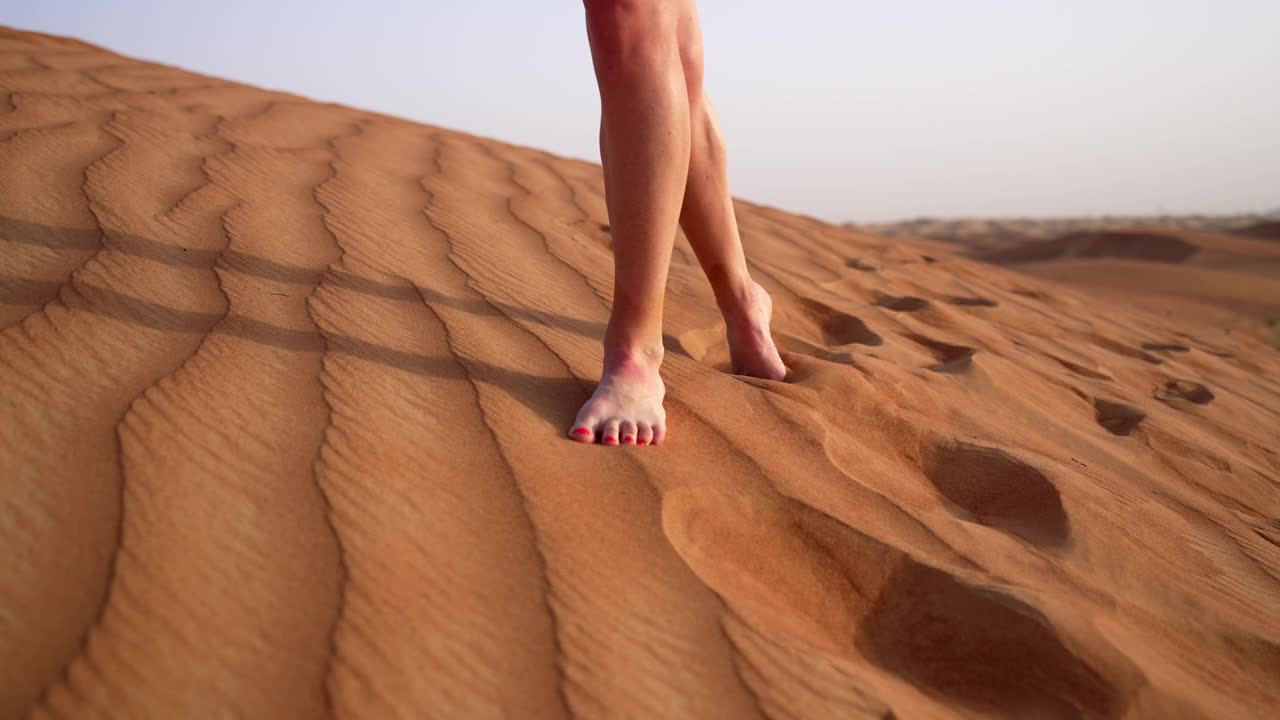 特写美女的腿穿着短裤走在沙漠上。享受旅行，在炎热的烈日下，在沙丘上呼吸新鲜空气。暑假在另一个国家度假。视频下载
