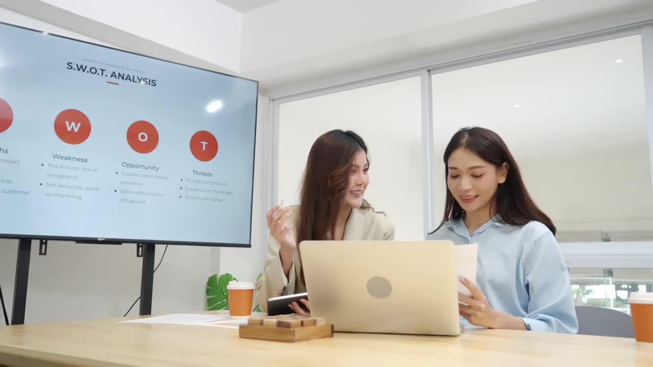 亚洲女商人使用笔记本电脑和平板电脑与同事在会议室进行头脑风暴视频素材