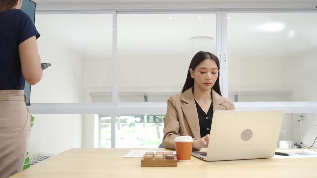 亚洲女商人使用笔记本电脑和平板电脑与同事在会议室进行头脑风暴视频素材