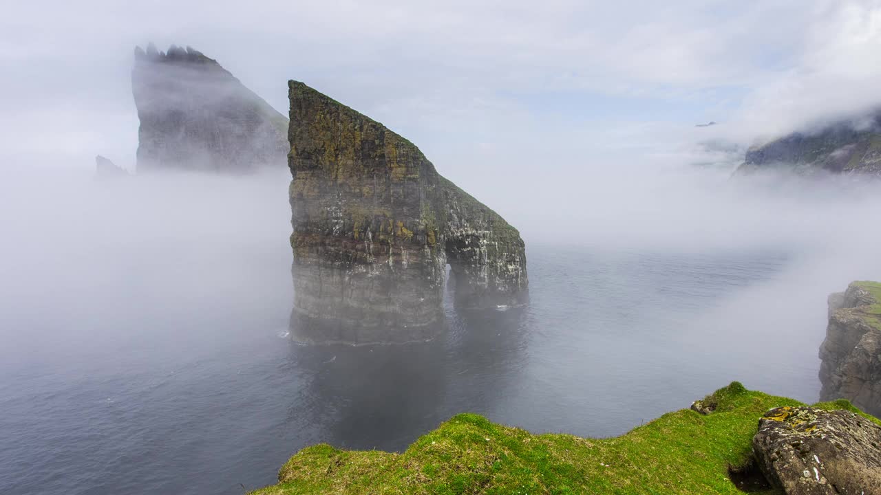 在丹麦法罗群岛的浓雾中，drangarir岩石的时间流逝视频下载