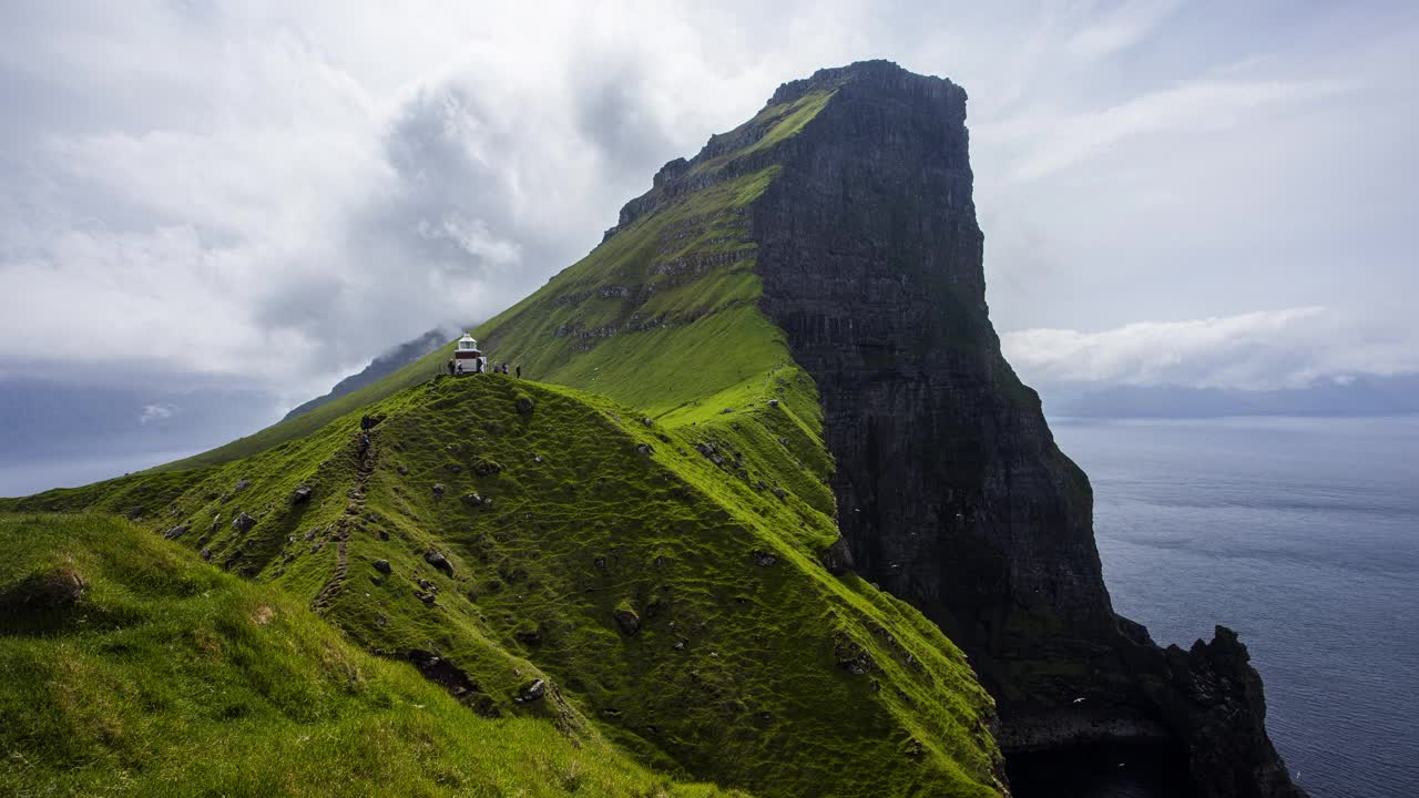 丹麦法罗群岛卡尔索伊岛绿色山丘上的卡卢尔灯塔的时间流逝。视频下载