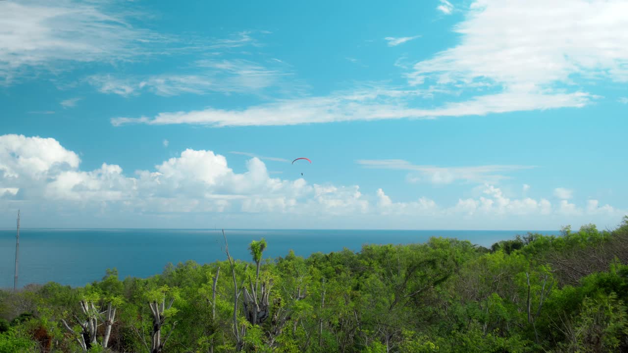 高空跳伞者在多云的天空中驾驶降落伞飞过海面视频下载