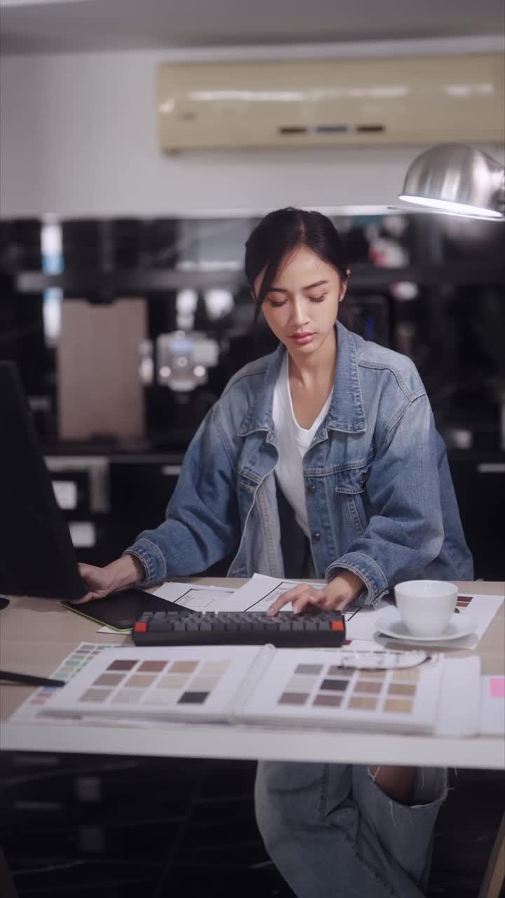 一位亚洲女建筑师，专注而专注，在现代办公环境中为产品进行计算机辅助设计时，正在与人通电话。视频下载