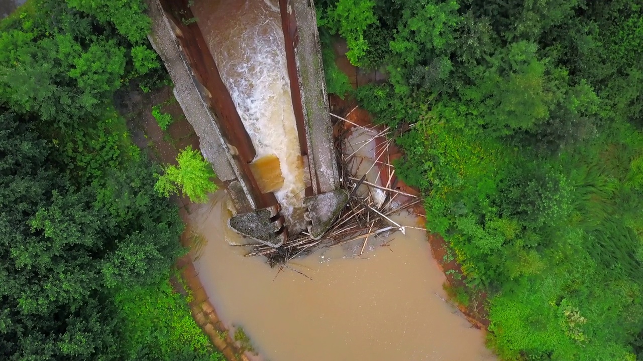 脏河上水坝的俯视图。夹。脏河上的工业水坝。大坝或大坝在棕色河流与绿色森林的床上视频下载
