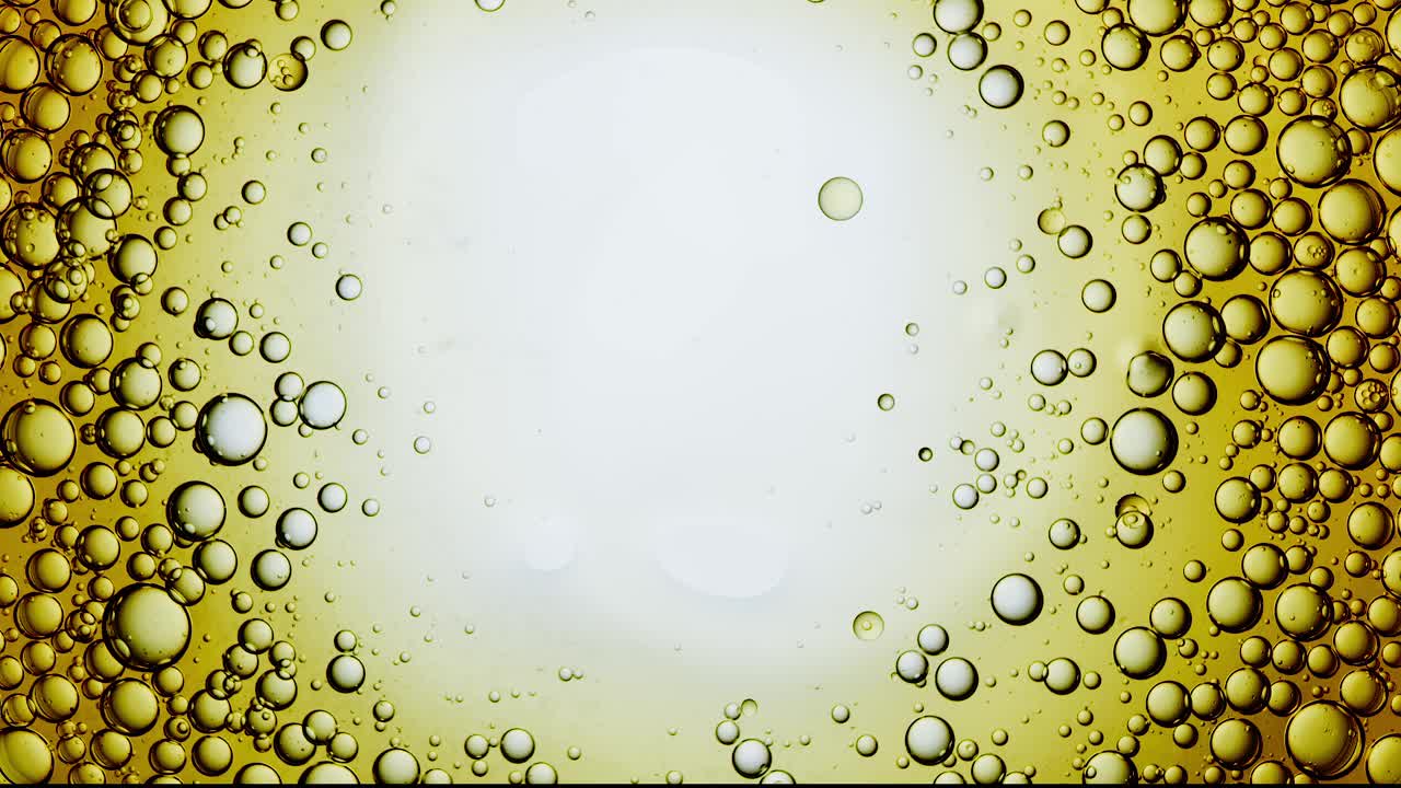 捕捉一个超级特写和慢动作的科学实验室的角度来看，无数浮动，生动的黄色油泡旋转，搅拌，并在水面上逆时针旋转。视频下载