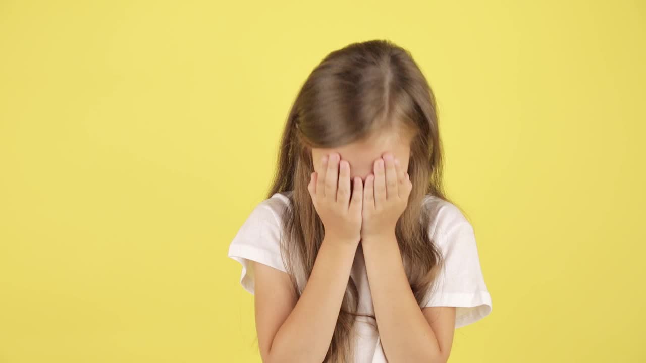 孩子的问题。画室里伤心的小女孩哭着擦眼泪，黄色背景。视频下载