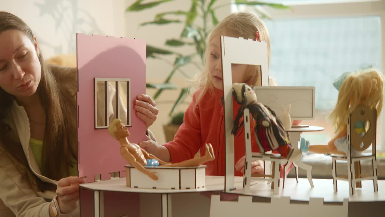 妈妈和可爱的女儿正在做一个娃娃的房子，墙上和窗户的细节视频下载