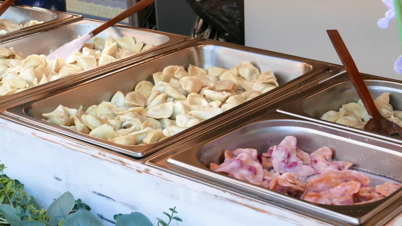许多不同口味的波兰传统经典饺子有不同的馅料出售，金属容器美食节市场摊位，餐厅服务。本土厨房饮食文化理念视频下载