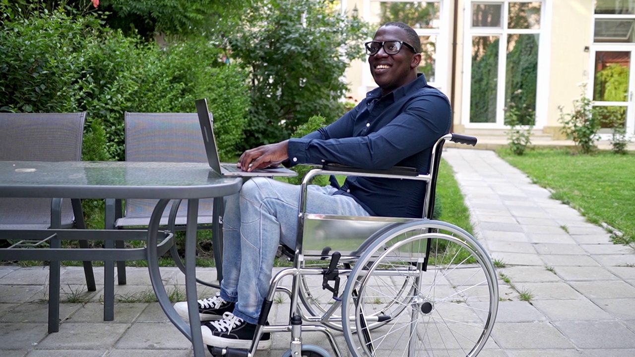 一个快乐的残疾人在笔记本电脑上工作，在花园里工作时面带微笑视频素材
