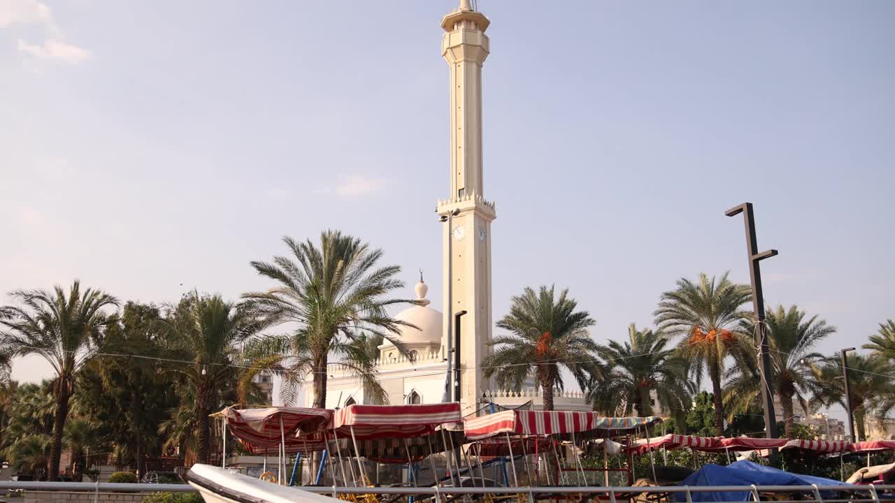 在黎巴嫩北部的黎波里附近的海滨小镇拉米纳，一座干净的现代尖塔矗立在棕榈树上视频下载