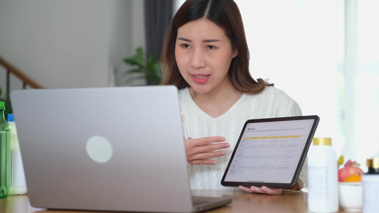年轻的亚洲女性营养师通过笔记本电脑为客户提供健康食品菜单建议，制作视频博客，直播健康食品视频下载