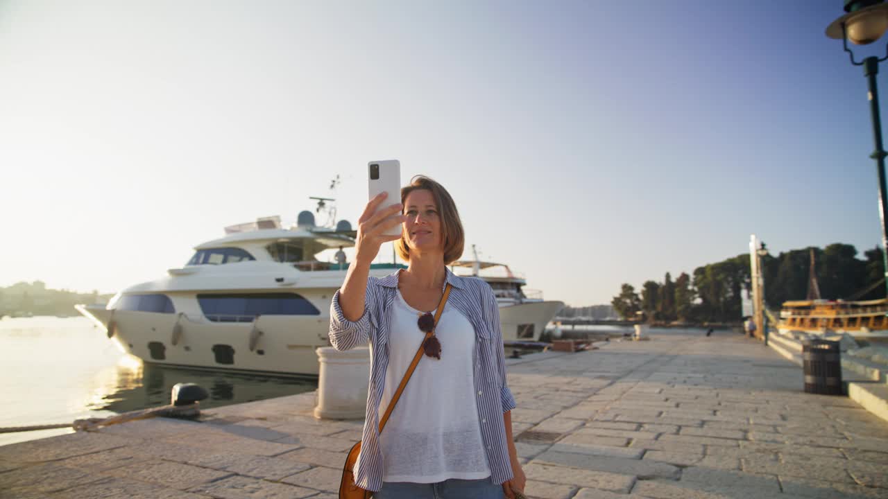 SLO MO 360°远景:女人用手机捕捉罗维尼海岸魅力的每一个角度视频下载