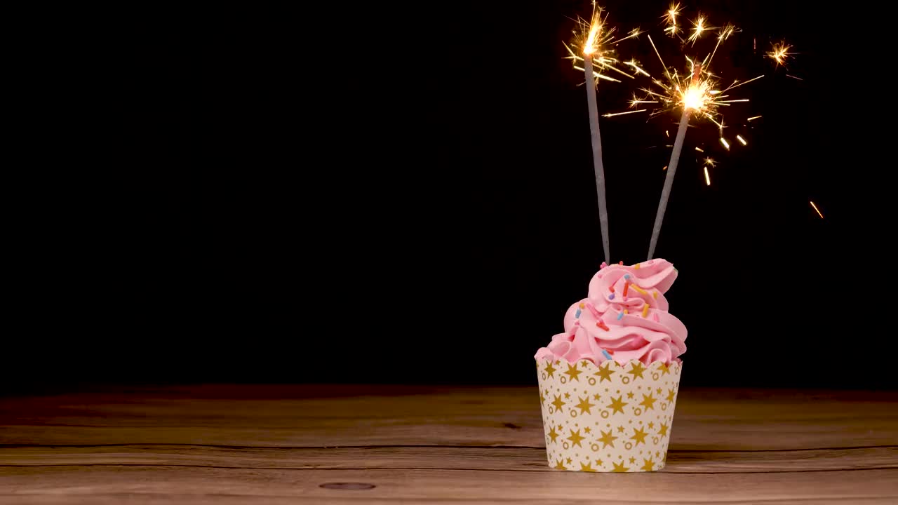 小蛋糕上有两个真正的燃烧的火花在黑色的生日派对上视频下载