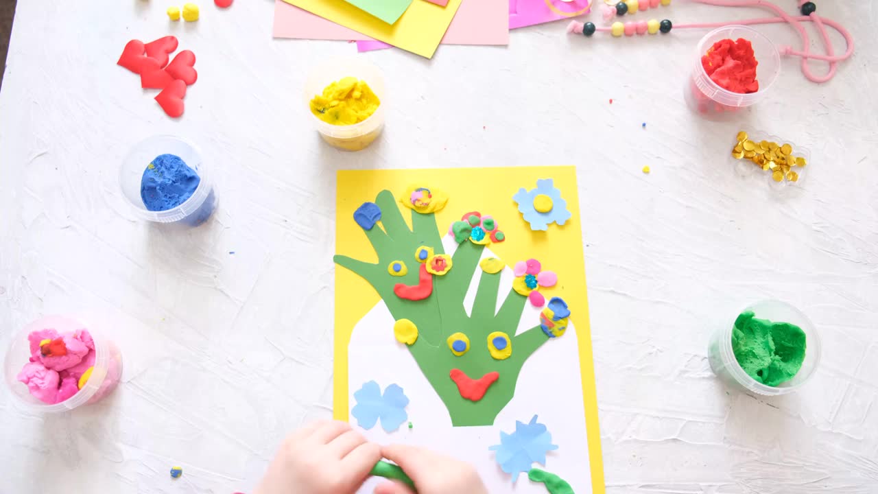 小女孩用五颜六色的粘土面团、橡皮泥和纸制作有趣可爱的贺卡。家庭教育。假期做准备。生日，母亲节，父亲节视频下载