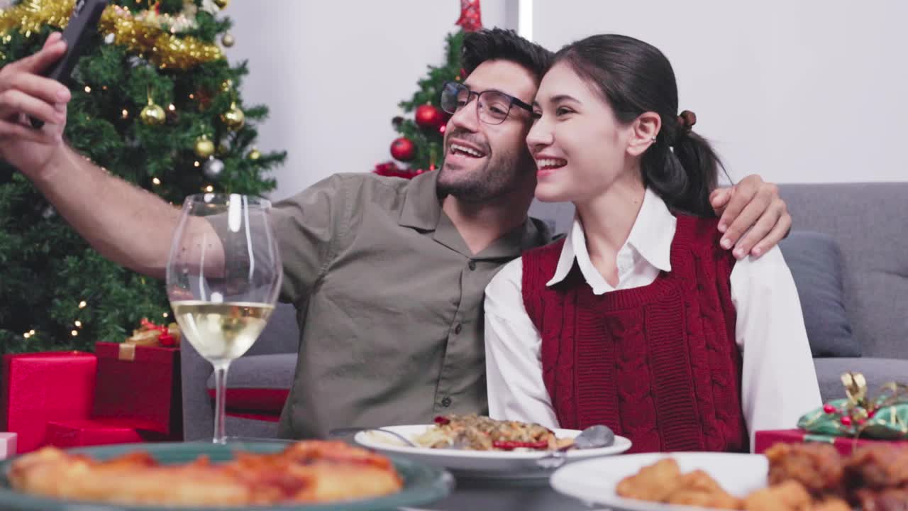 快乐的年轻夫妇视频电话与朋友在家里庆祝圣诞节视频下载