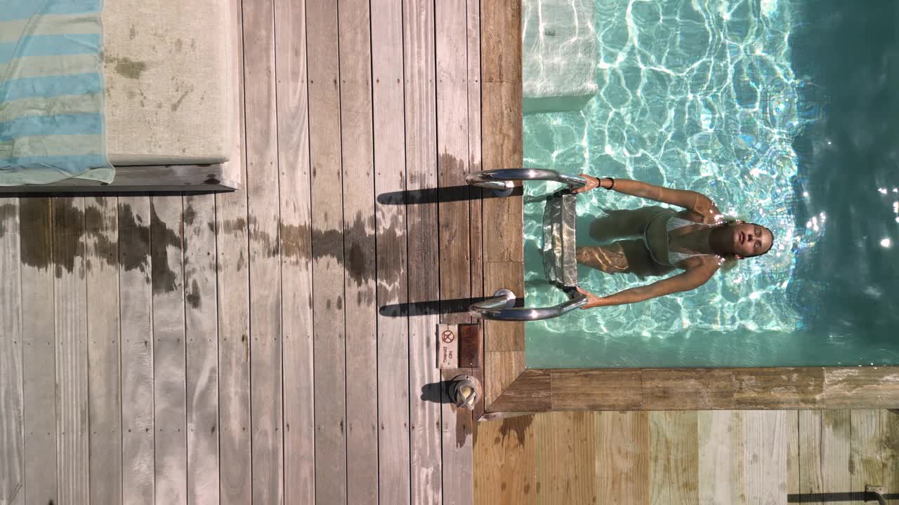 上图是一名女子从泳池里出来，在海边旅游胜地的躺椅上晒日光浴。视频下载