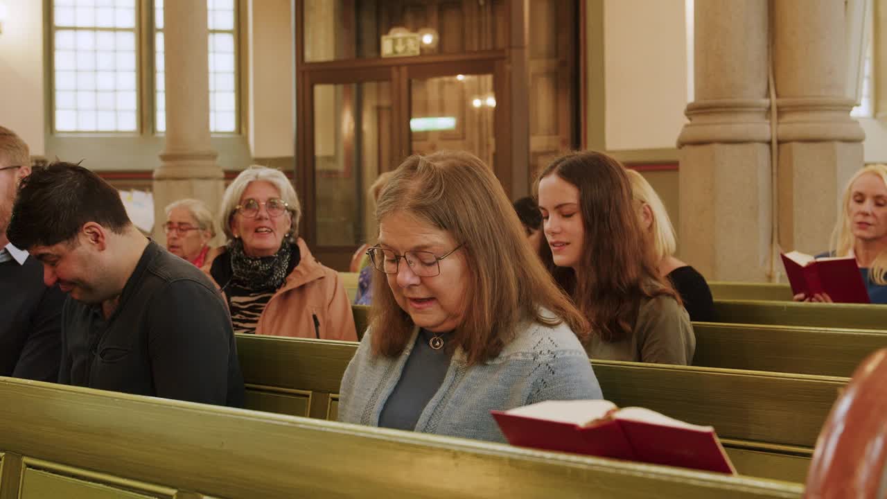 在教堂的弥撒中，男新教徒和女新教徒坐在长椅上唱圣歌视频下载