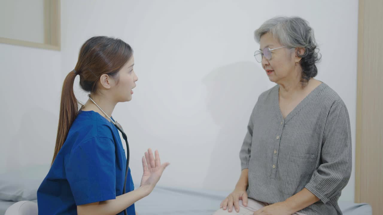 亚洲青年女医生在医院里用听诊器听老年妇女病人的心脏，检查老年妇女的健康，检查成熟中年妇女的肺部。视频下载