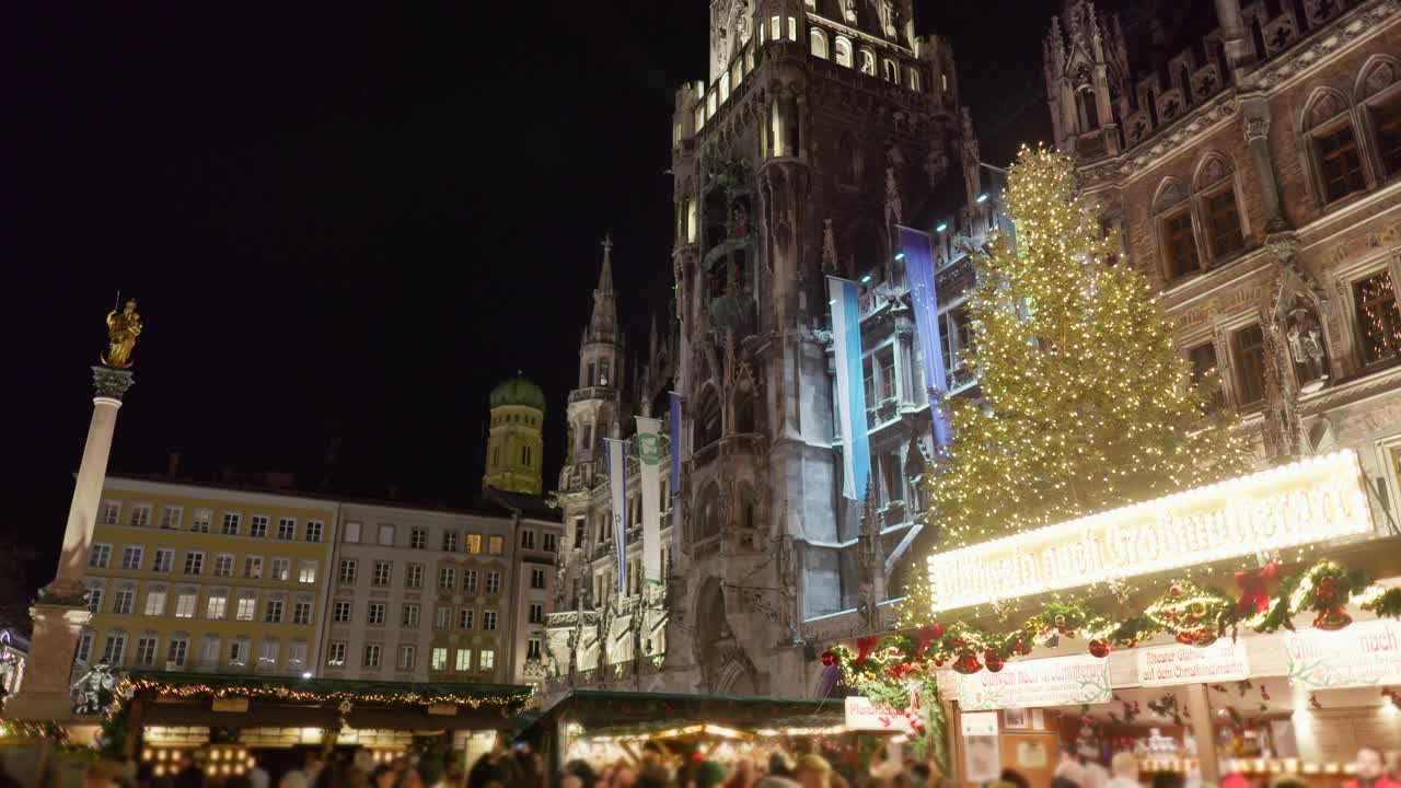 慕尼黑玛丽恩广场的圣诞市场，在夜晚，市场摊位在前景和背景的新议会。视频下载