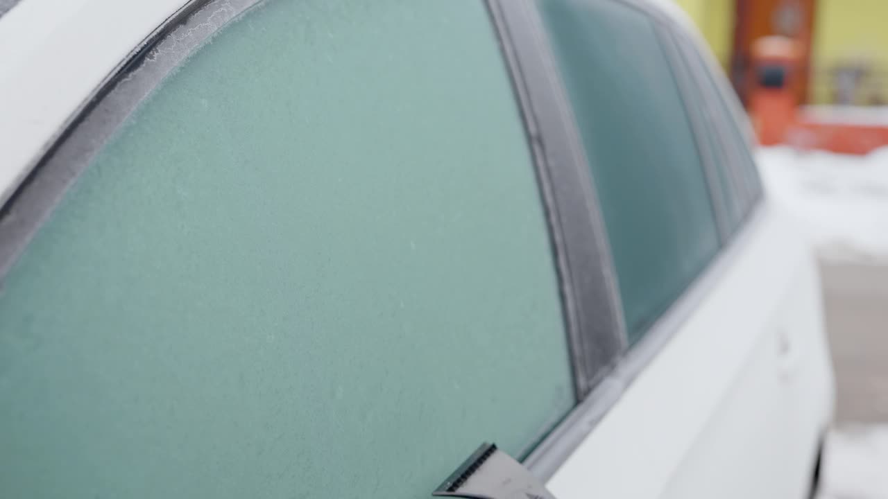 在一个寒冷的冬天早晨，窗外的景色，一名男子擦着他汽车的侧窗视频下载