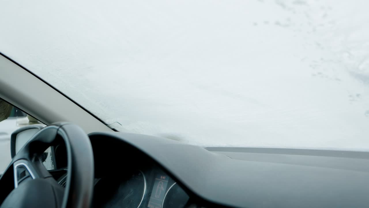 在一个寒冷的冬天早晨，一个男人刮掉他汽车前窗上的霜视频下载