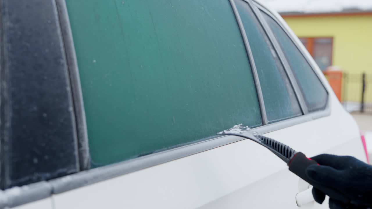 在一个寒冷的冬天的早晨，外面的景色中，一个男人在抓挠他的汽车侧窗视频下载