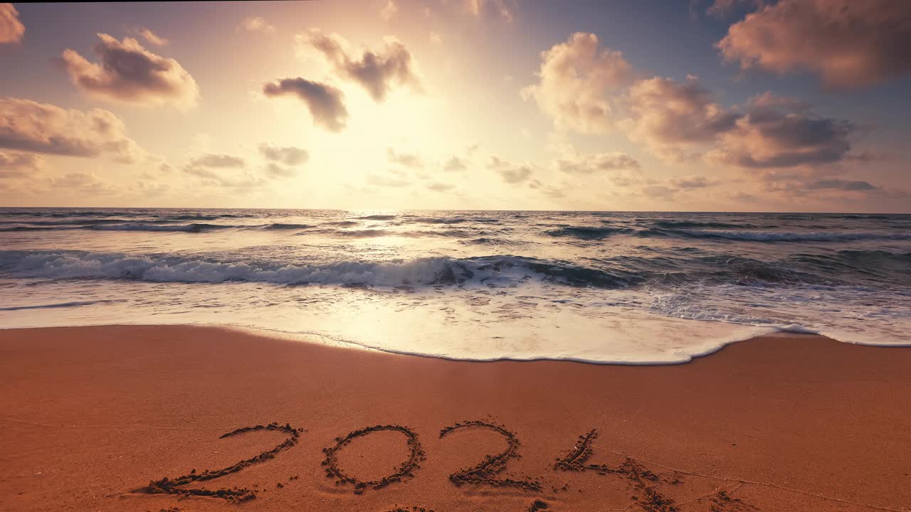 2024年新年的文字写在沙滩上的热带海滩，在美丽的日出，云在海浪和异国情调的岛屿视频购买