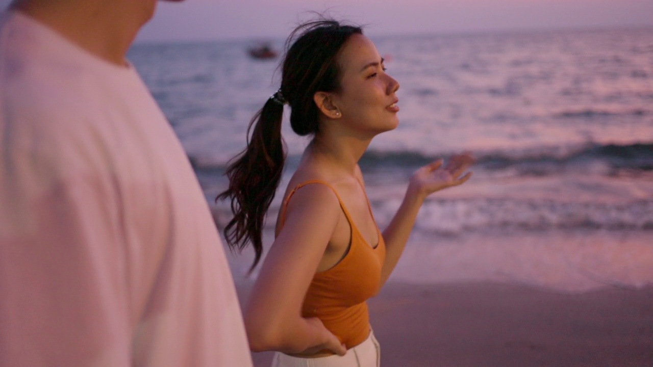 一对亚洲夫妇在沙滩上享受运动后黄昏的浪漫时刻视频下载