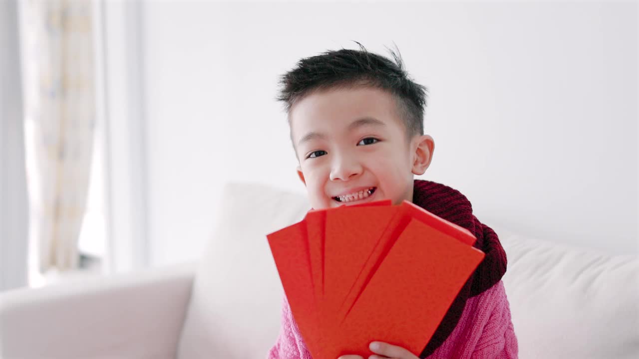 快乐的亚洲男孩展示并拿着红包。快乐的中国新年概念。视频下载