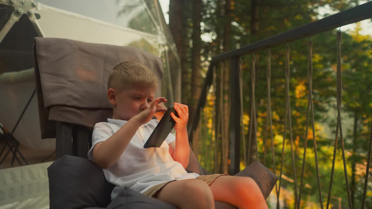 男孩用手机享受度假的豪华野营计划视频下载